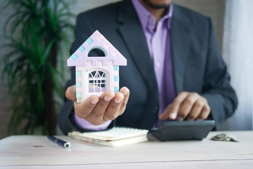 man holding model house at desk with calculator; HELOC in Cumberland County