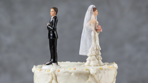A bride and groom wedding cake topper, with the couple facing away from each other.