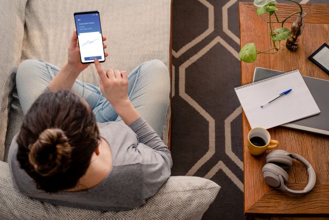 Person using investing app on phone while sitting next to desk