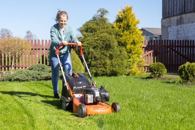 Teenage girl mowing lawn