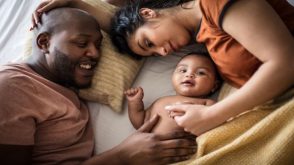 Mother and father laying on bed with baby