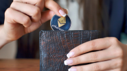 Woman placing Bitcoin token into wallet