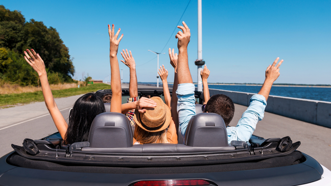 Young people enjoying a convertible rental car on the coast