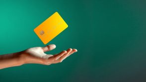 A hand tossing a credit card in the air, in front of a green background