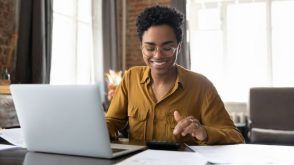 A young, smiling woman working on taxes in front of a computer