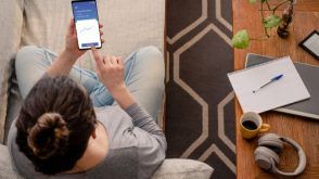 Woman sitting on a couch looking at investments on her smartphone