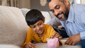 Father and child putting a coin into a piggy bank