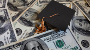 Graduation cap on a pile of $100 bills