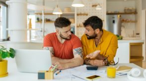 Two men looking over paperwork in front of a laptop