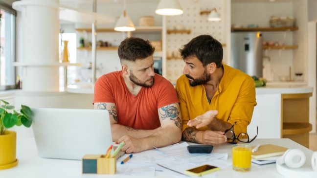 Two men looking over paperwork in front of a laptop