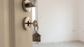 new_home_key A house keychain dangling from a key in a door lock