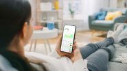 Woman sitting on a couch, holding a smartphone showing a stock graph