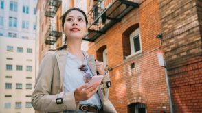 Young woman walking through a neighbourhood with a phone in her hand