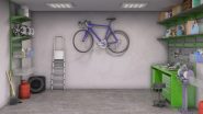 Interior of a clean and organized house garage, with a ladder, bicycle on the wall, and green workbench.