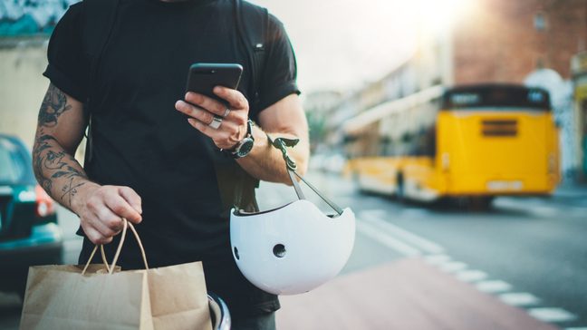 Tattooed Man courier using a map app on mobile phone
