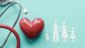 A stethoscope, ceramic heart, and paper dolls of a family