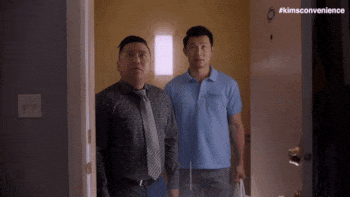 A gif of two men standing in a doorway as water pours down from the ceiling.