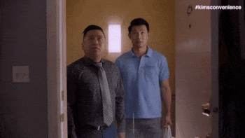 GIF dua pria berdiri di ambang pintu saat air mengalir dari langit-langit.