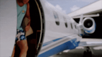 A gif of a Millennial man dressed in shorts, climbing down from a private plane and lowering his sunglasses. 