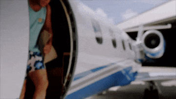 A gif of a Millennial man dressed in shorts, climbing down from a private plane and lowering his sunglasses.