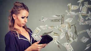 A woman holding a wallet with money flying out of it