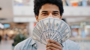 Petal 2 Review: Fee-Free Rewards and Credit-Building Man holds several bills in front of his face while smiling