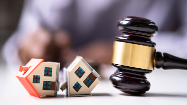 Two toy houses collapsed next to a gavel
