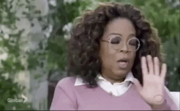 A gif of Oprah turning her head to one side and waving her hands in front of her in a "hang on a moment" gesture.