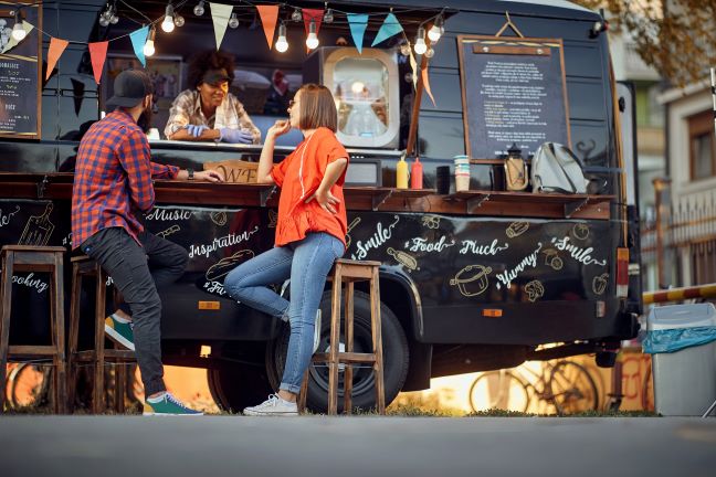 People standing in front of food truck talking to cook