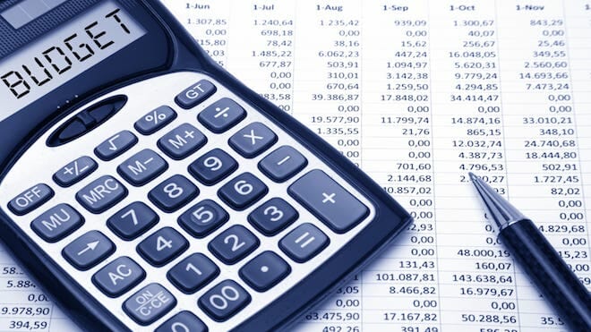 Tools for budgeting including a calculator with the word budget on it and a pen in front of a spreadsheet