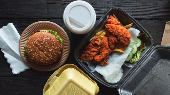 Takeout food including burger, chicken tenders, fries, and drink