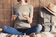 Woman sitting cross-legged while using credit card on smart phone