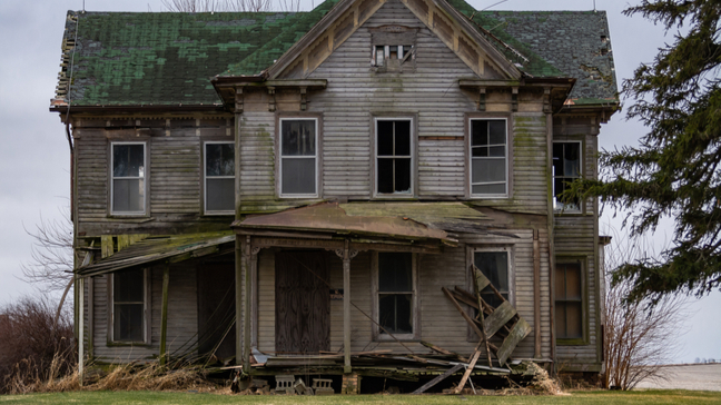 abandoned home with unkept yard and broken facade