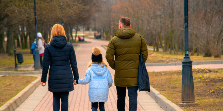 A family holding hands walking in a park. From "The average cost of term life insurance by age."
