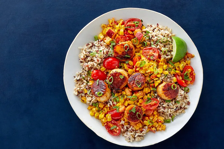 Photograph of pan-seared scallops and red rice with charred corn and peach salsa from Blue Apron.