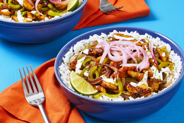 Photograph of citrus chicken and pepper bowl with garlic rice, pickled onion and lime crema from EveryPlate.