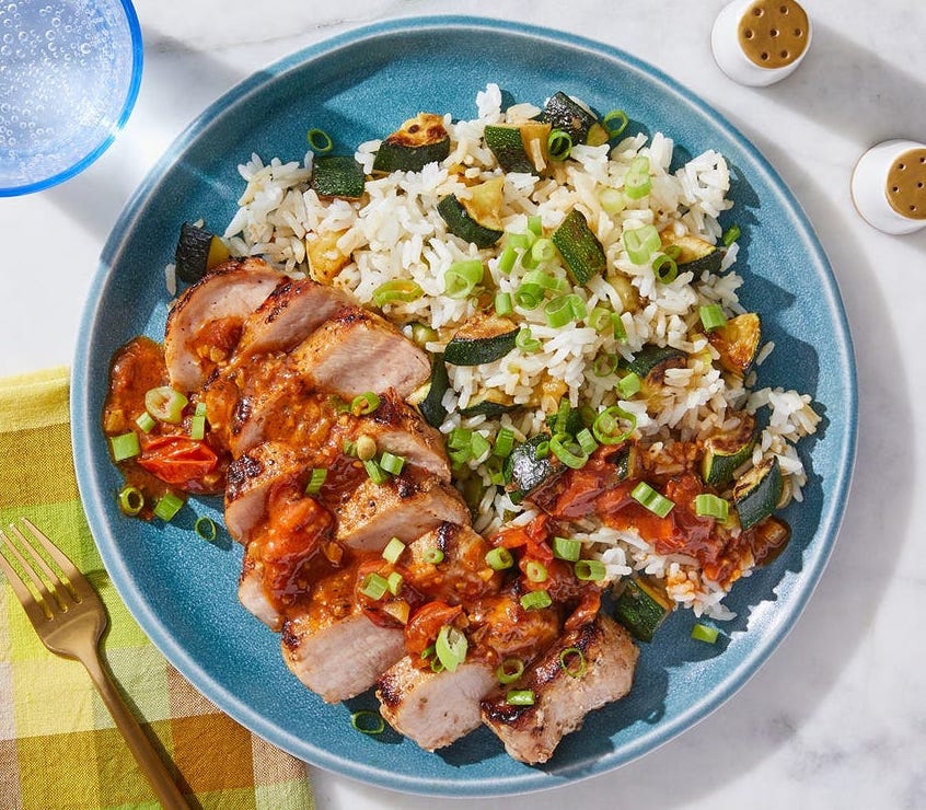 Photograph of pork chops with tomato pan sauce and zucchini from a Blue Apron meal kit.