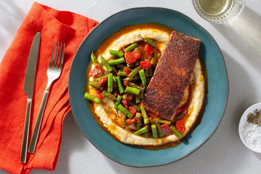 Photo of prepared Creole-spiced salmon with tomatoey green beans and cheesy grits from a Sunbasket meal kit.