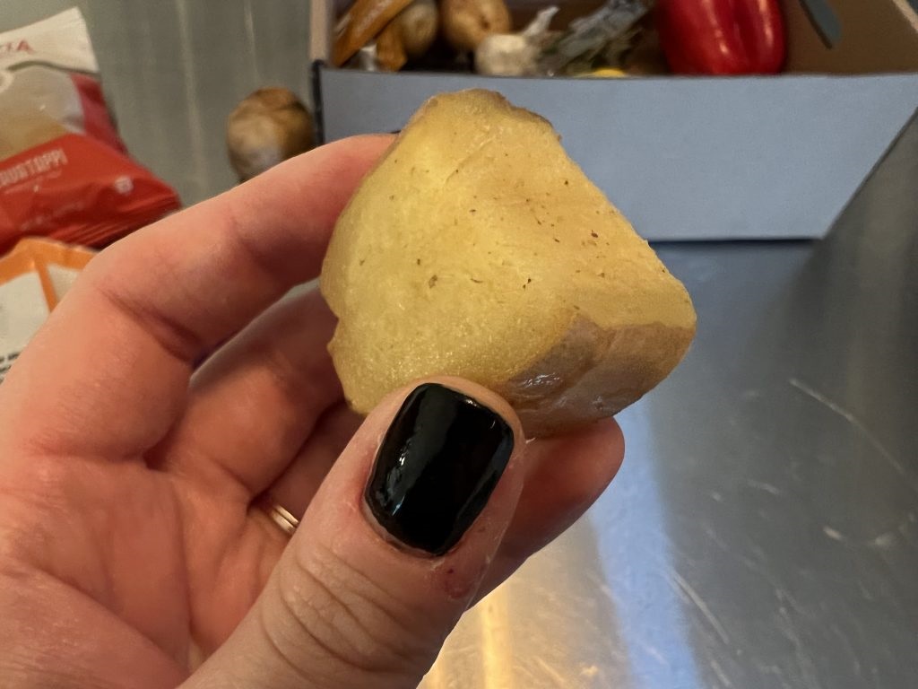 Piece of ginger from EveryPlate held in hand against kitchen backdrop