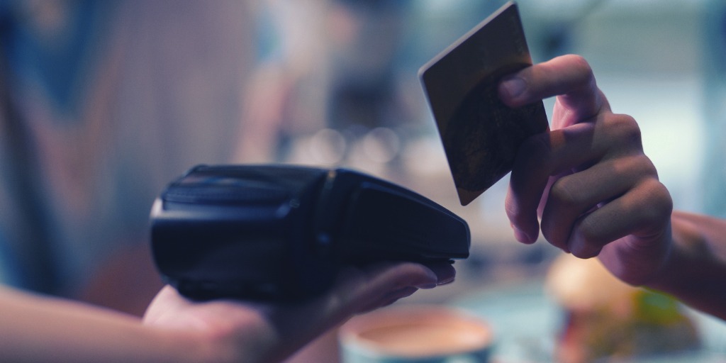 payment with debit card at sale terminal with coffee shop background. From "Does your debit card have a daily spending limit?"