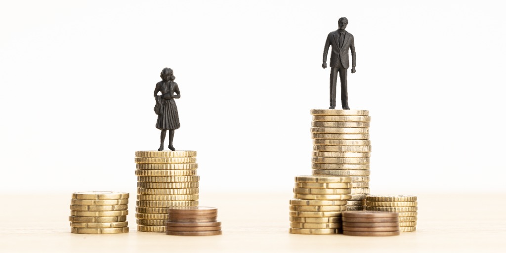 male and female figurines set on top of stacks of coins for visualization of pay gap difference. From "9 strategies for narrowing the gender pay gap".