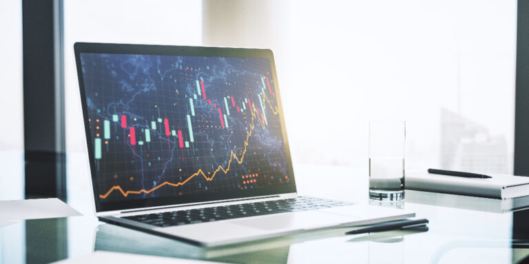 A laptop on a desk showing a stock performance chart.
