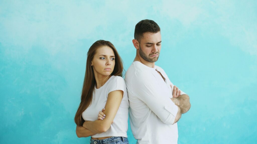 Couple standing back to back with arms crossed; financial Infidelity