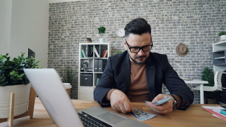 a man sitting at a table in front of a laptop; funding life's biggest investments