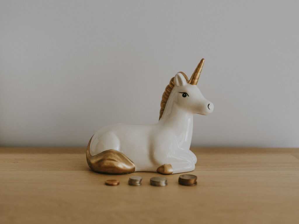 white and gold ceramic unicorn figurine near coins; passive income