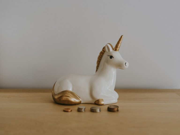 white and gold ceramic unicorn figurine near coins; passive income