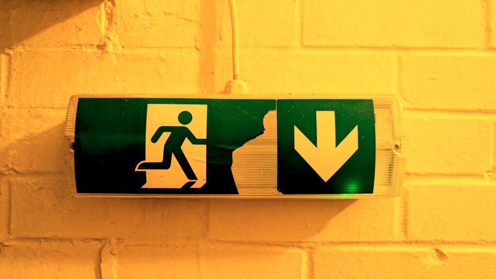 Emergency exit sign is illuminated on a wall; osha