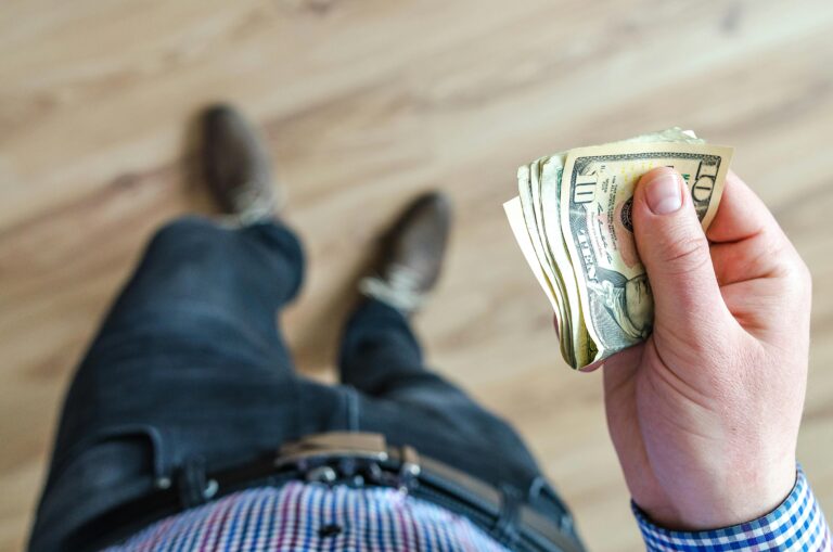 young person making financial mistakes holding $10 bills