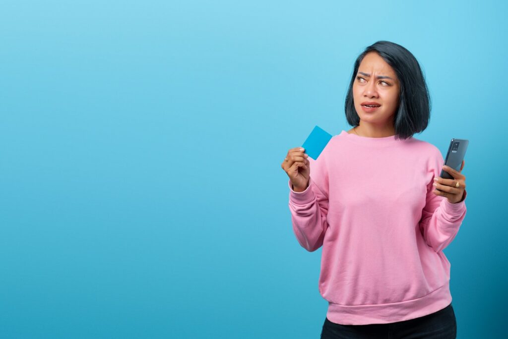 a woman holding a cell phone and a credit card; Fed rate hike