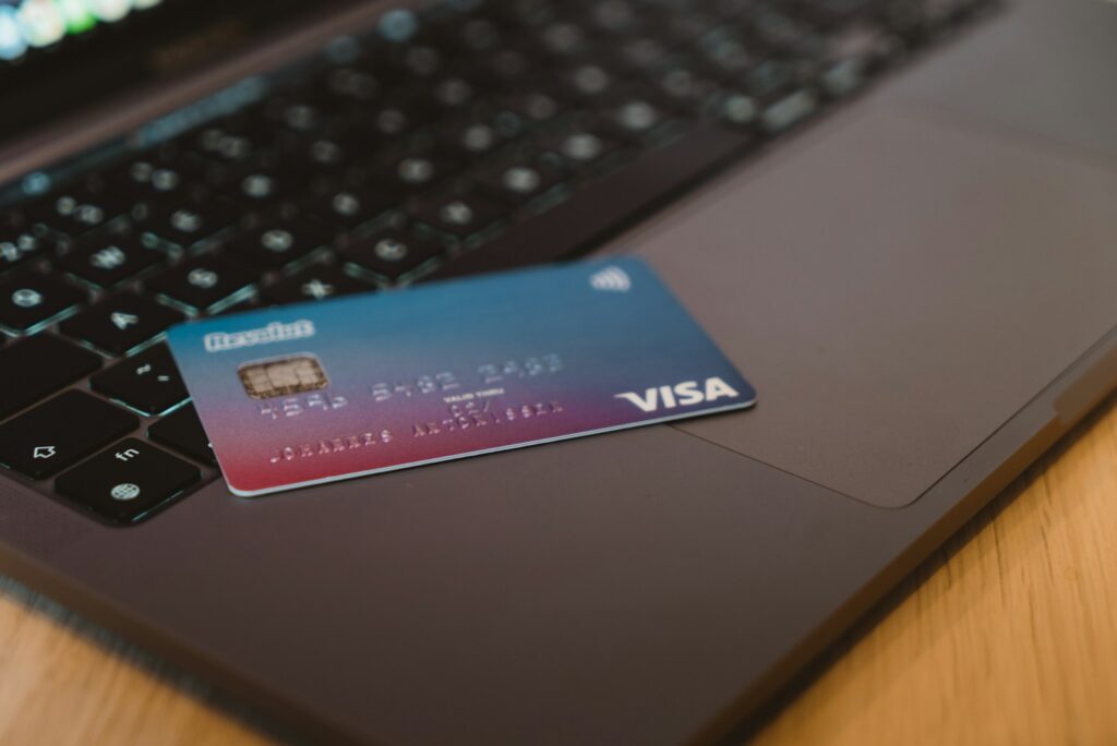 A blue and red gradient debit card resting on a dark laptop keyboard; credit card balances fell